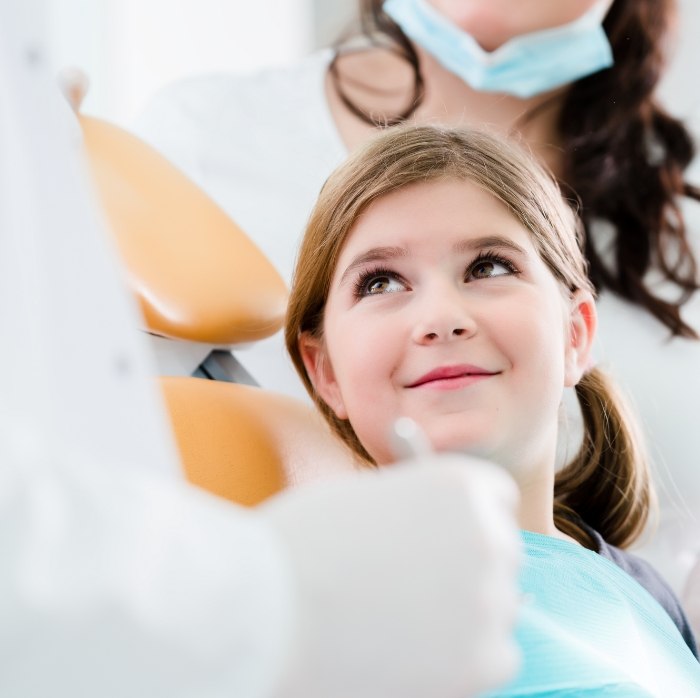 Young girl in dental chair smiling at her dentist