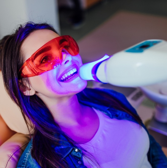 Woman getting professional teeth whitening in dental office