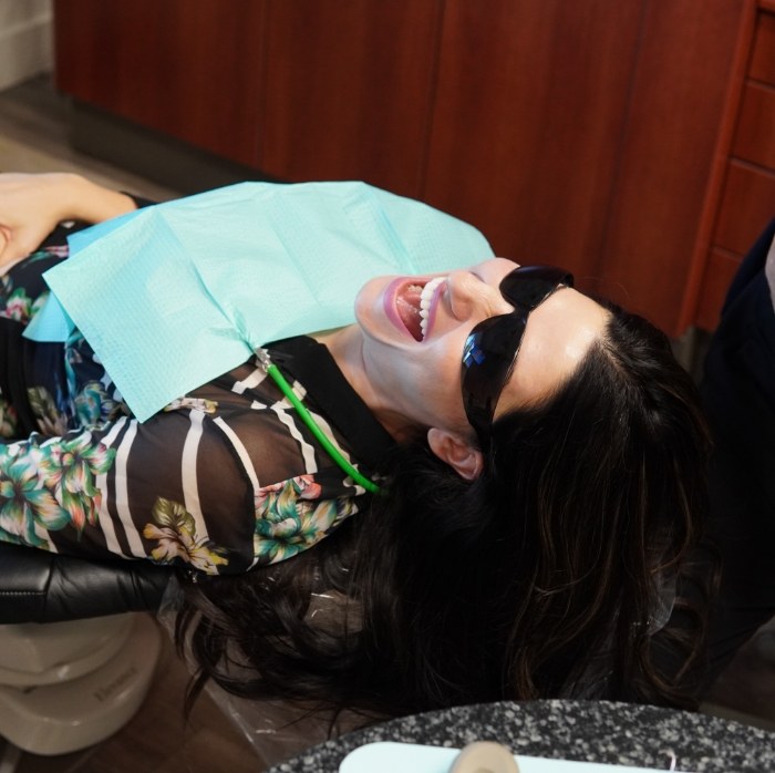 Dental patient in sunglasses and dental bib grinning wide