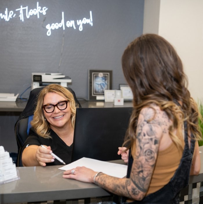 Dental receptionist handing a clipboard to a patient