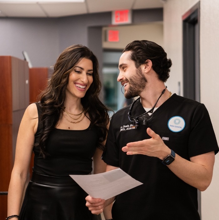 Doctor Raiffe standing next to a patient showing them a paper