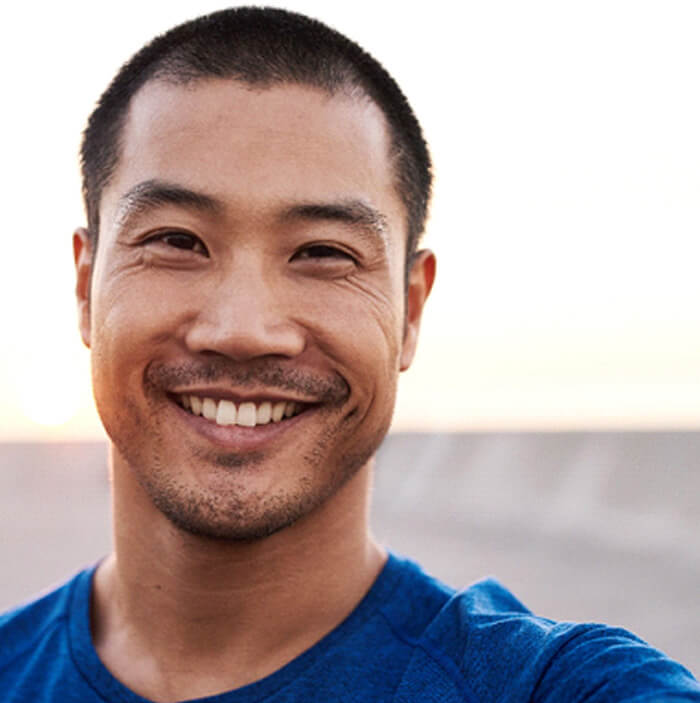 man smiling while taking selfie outside