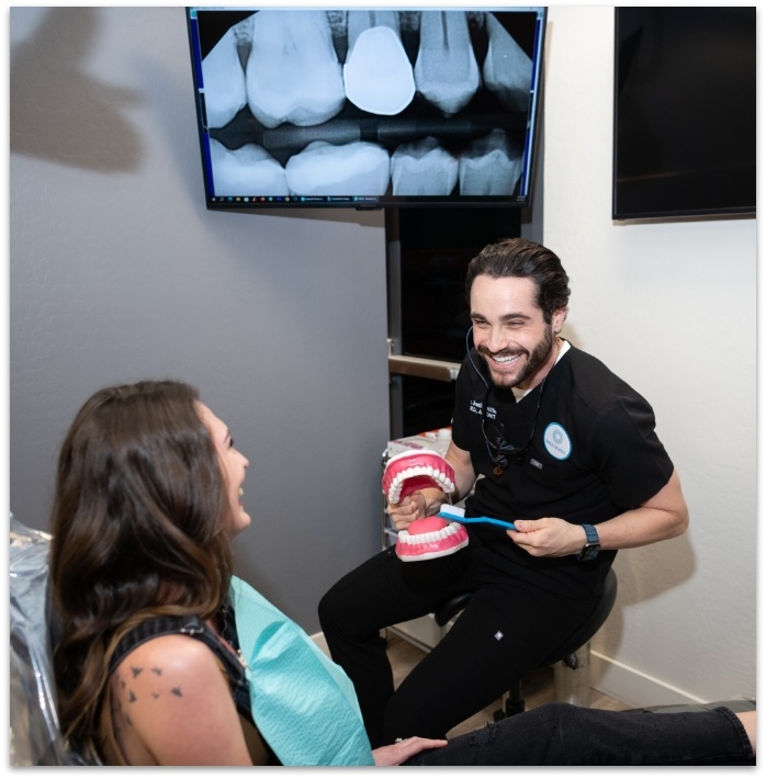 Doctor Raiffe brushing model of teeth with a dental patient