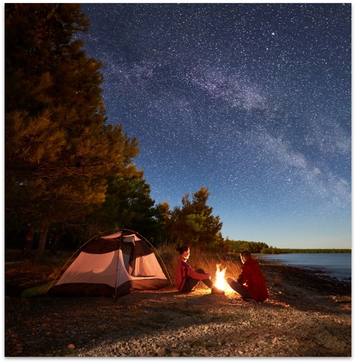 Two people sitting at a campfire at night