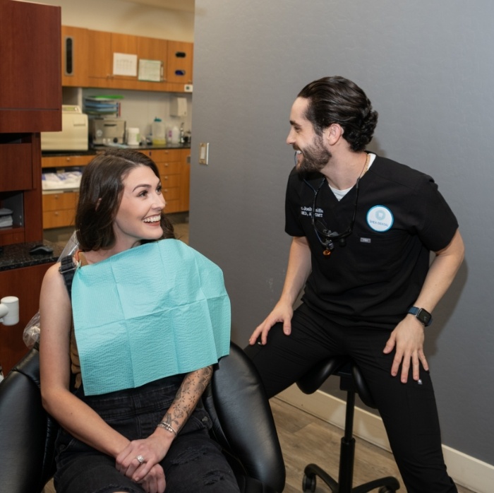 Woman in dental chair laughing with her dentist