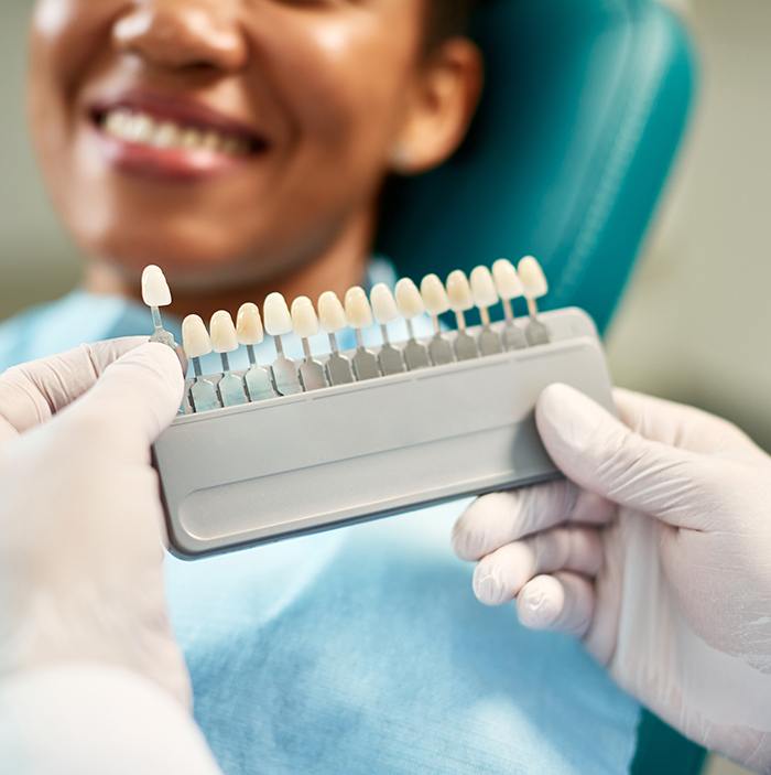 Dentist helping smiling patient select shade of veneer