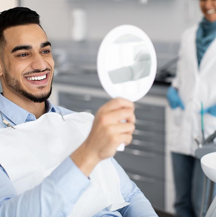Man smiling at reflection in mirror in treatment chair