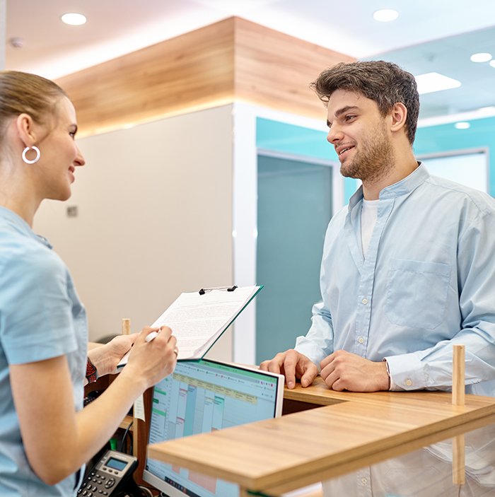 Patient and dental receptionist smiling in lobby